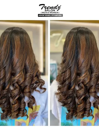 A stunning example of rich, multi-tonal hair color styled into perfect, bouncy curls. The highlights add depth and dimension.