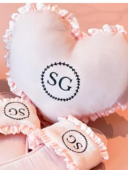 A matching set of a personalized heart-shaped pillow and slippers, embroidered with the bride's initials.