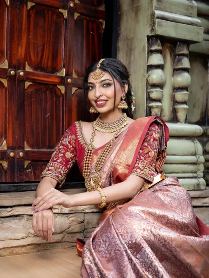 A beautiful smile completes the look. This bride is wearing a traditional temple jewellery set with a peacock-motif long haaram, a perfect choice for a South Indian wedding.