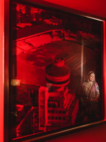 An artistic and creative bridal portrait, using a red-lit reflection to create a dramatic and unique image.