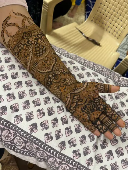 This full-arm design showcases a variety of patterns, including paisleys, checks, and floral elements, creating a rich tapestry of henna art.