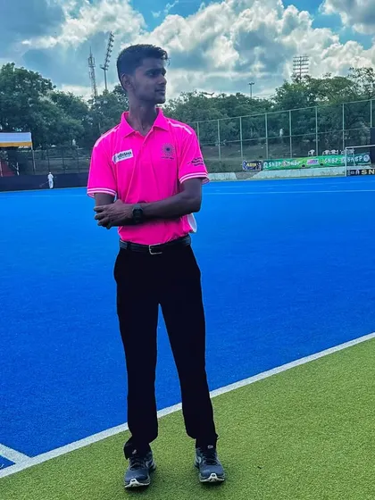 Shyam Sharma, one of our rising stars, standing on the blue turf of the SNBP Hockey Tournament. We support our players in pursuing roles as match officials.