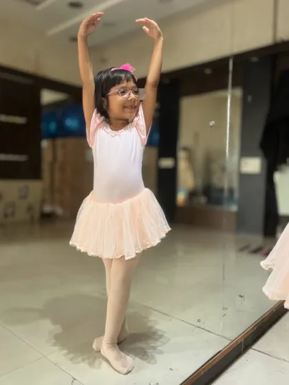 A young student practices her poses in a pink leotard and tutu. Proper attire is encouraged in my ballet classes to help with movement and discipline.