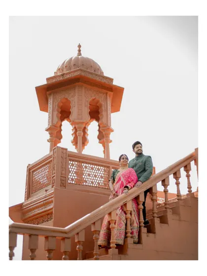 A majestic pre-wedding portrait of the couple posing on the stairs of a grand, traditional structure, creating a regal and impressive image.