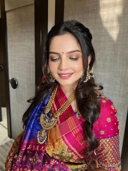 A close-up of the Godh Bharai makeup. The soft peachy-pink hues on the eyes are blended with shimmer, while a hint of blue liner adds a playful, modern touch.