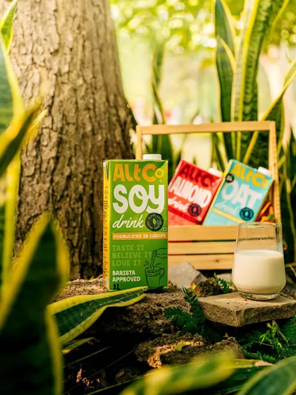 Alt Co.'s plant-based milks nestled in a wooden crate amidst lush greenery. This shot reinforces the brand's "plant-powered" message with a strong, natural aesthetic.