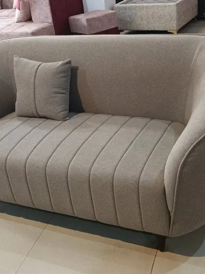 A custom-made two-seater sofa with vertical channel tufting and a gracefully curved frame. This piece is an example of our bespoke furniture, designed for both comfort and style.