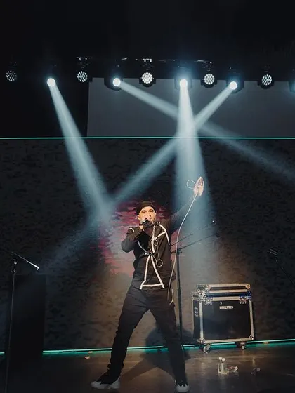 A solo performer on the dark, dramatically lit stage, creating a powerful and intimate moment during the Sangeet.