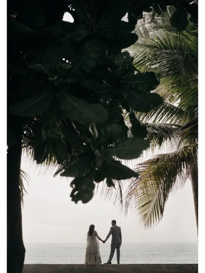 A silhouette of the couple holding hands against the sea, framed by palm trees. This is a classic, romantic shot for any destination pre-wedding.