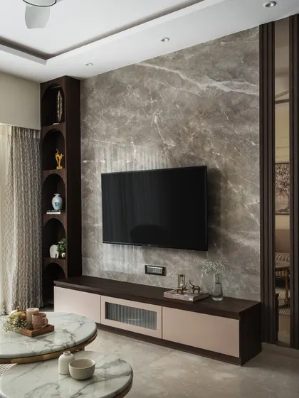 The TV wall is clad in luxurious Italian marble, with integrated curved niches designed to showcase the homeowner's collection of artifacts. This feature adds a personal and refined touch to the entertainment area.