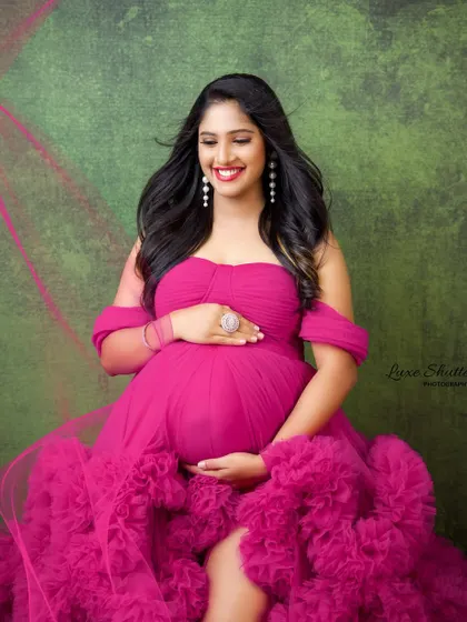 A close-up look at the radiant smile of this mom-to-be, beautifully framed by the soft ruffles of her pink gown.