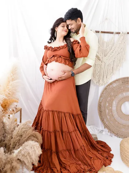A beautiful couple's portrait in a rustic, boho-themed setup. The earthy tones of the outfits and decor create a warm and natural feel.