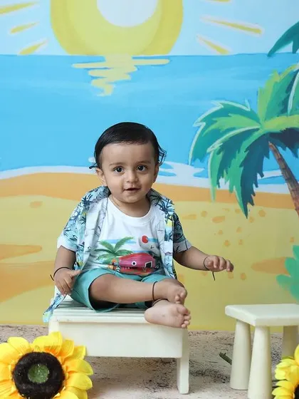 A sweet, direct-to-camera look from the toddler in his beach outfit, without the sunglasses.