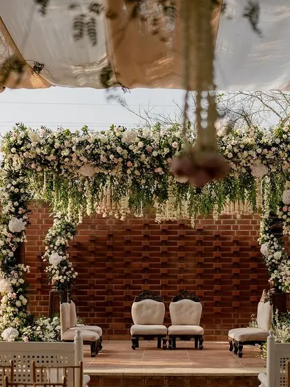 A full view of the elegant engagement mandap at The Secret Grove, showcasing the floral arch, the classic seating for the couple, and the overall romantic ambiance created by the design.
