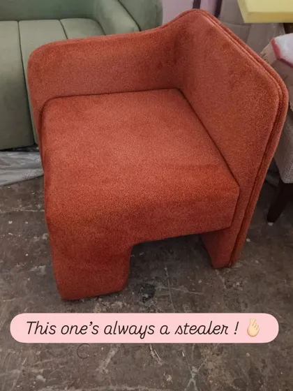 This one's always a stealer. A contemporary accent chair in a burnt orange fabric, featuring a unique, angular design that makes it a true statement piece. Its compact form is perfect for adding a pop of color and style to any corner.