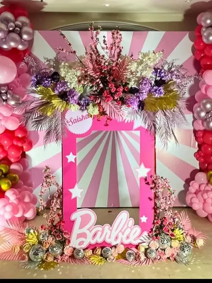 A fun and interactive Barbie-box-style photo frame, decorated with flowers and stars, perfect for guests to pose in.