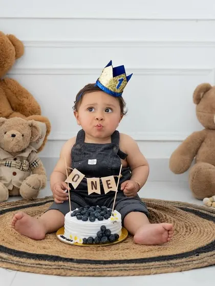 A funny face before the cake smash begins. This teddy bear themed setup is perfect for capturing all the cute and quirky expressions of a one-year-old.