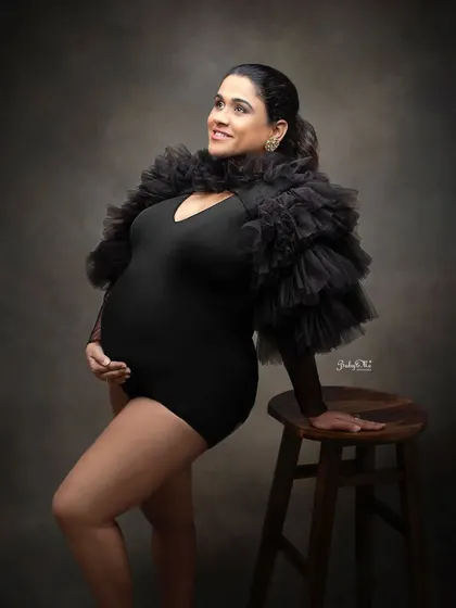 A powerful and confident pose from this stunning mama. The black ruffled bodysuit paired with a simple wooden stool creates a chic and modern maternity portrait.