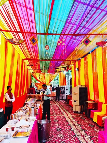 I can turn any open space into a grand celebration area. This is a housewarming party setup in a large outdoor area, fully covered with a colorful canopy of fabric drapes, showing how I manage large-scale event decorations.