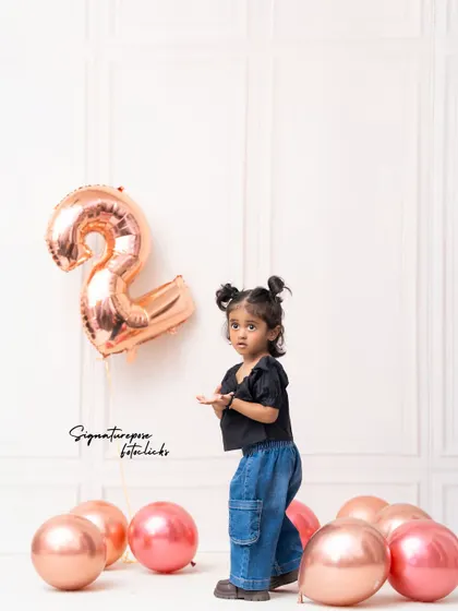 A standing portrait of the two-year-old birthday girl, showing off her cute pigtails and trendy outfit.