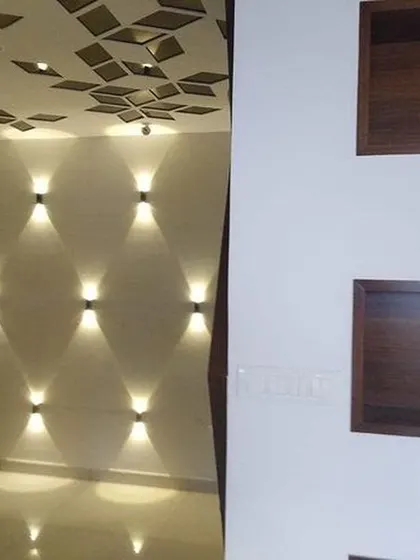 This image showcases creative wall lighting and ceiling details. On the left, decorative wall sconces create an artistic light pattern, while the ceiling features a geometric cutout design.