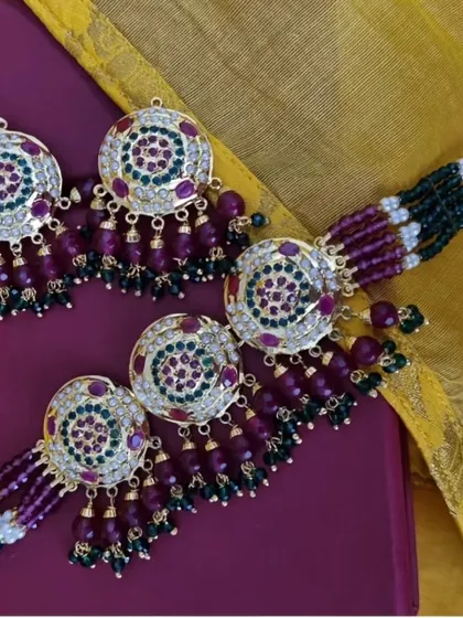 The 'रुकमणि' (Rukmani) Jadau set, featuring circular motifs with rich purple and green stones. This is a vibrant and festive piece, perfect for adding a splash of colour.