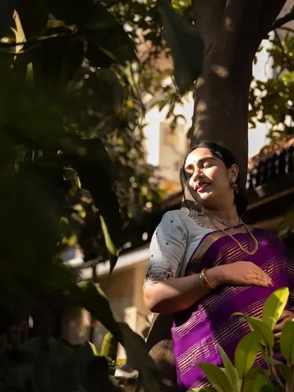A candid maternity portrait, with the mother-to-be enjoying a moment of peace in a garden. The natural light filtering through the leaves creates a beautiful, tranquil mood.