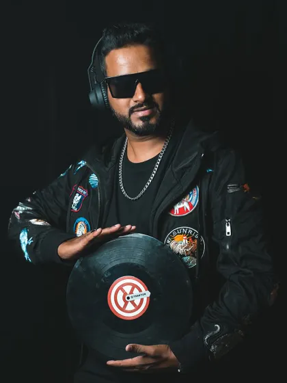 A professional headshot holding a vinyl record. This image bridges the classic art of DJing with a modern, stylish presentation.