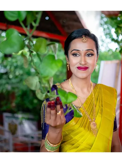 A lovely portrait of the bride in her yellow saree, holding a green leaf, connecting with nature.