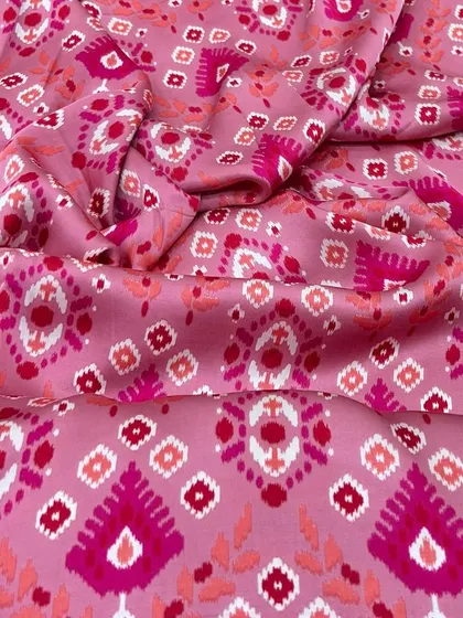 A close-up of our pink modal satin with a vibrant ikat-inspired print, showcasing its soft texture and beautiful colors.
