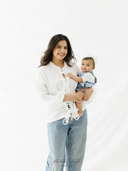 A full-length portrait showcasing the effortless style and love of a mother and her child. The clean, white background keeps the image fresh and timeless.