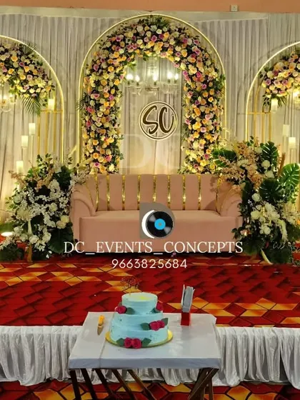 An elegant reception stage with three floral arches and hanging chandeliers. This symmetrical design provides a grand and classic backdrop, complete with a custom monogram for a personal touch.