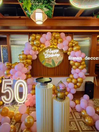 A still photo of the elegant 50th birthday decor, showing the circular balloon arch, light-up number, and decorative plinths.