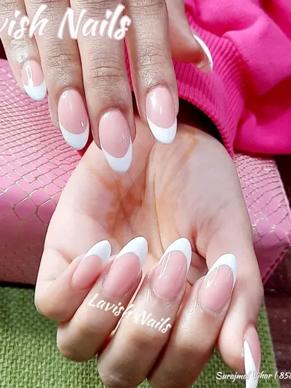 This image highlights the crisp white tips and sheer pink base of a classic French manicure on long, elegant almond nails.