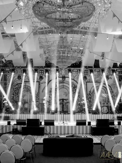 A black and white shot of the stage setup for the 'Borough Bazaar' event. The dramatic lighting and grand chandeliers highlight the scale and elegance of the production.