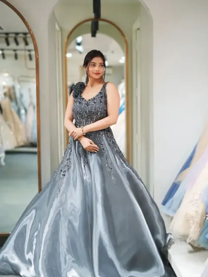 A beautiful grey satin ball gown with a full, flowing skirt and an intricately beaded bodice. The one-shoulder detail adds a modern touch to this classic princess silhouette.