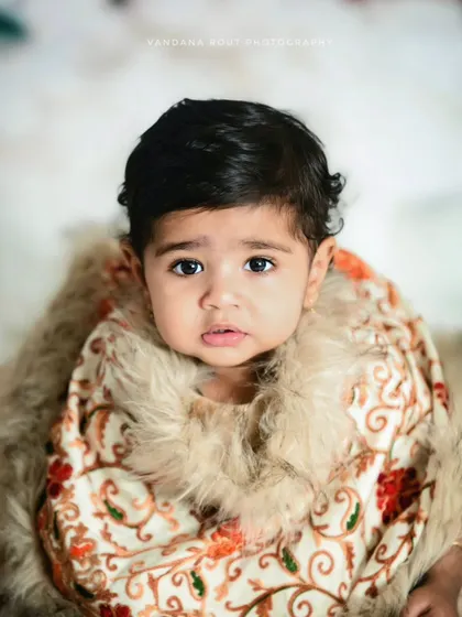 A close-up portrait from the winter-themed session. The baby's big, curious eyes and the detailed, cozy outfit make this an incredibly sweet and captivating shot.
