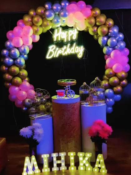 A colorful and fun birthday setup for Mihika, with a multi-colored balloon ring and a dark backdrop that makes the colors pop.