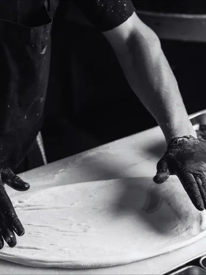 A black and white action shot of my hands stretching the pizza dough. It's a physical, hands-on process that requires skill and practice.
