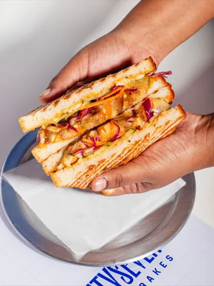 A cross-section of my Togarashi Chicken Melt Sandwich. You can see the layers of teriyaki glazed chicken, spicy yuzu slaw, and melty cheese in my soft Milk & Honey Loaf.