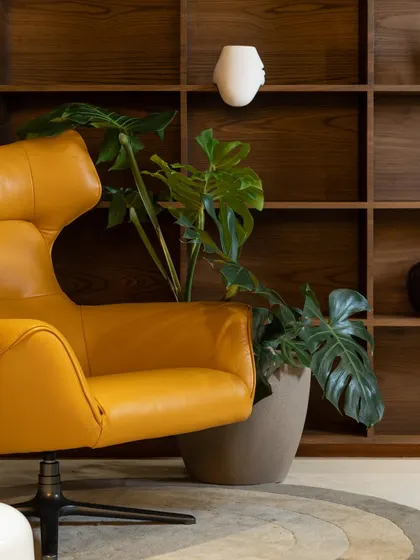 A detail shot of a bold mustard-yellow lounge chair set against a custom wooden bookshelf. This corner shows our love for using statement furniture and natural textures to create visual interest.
