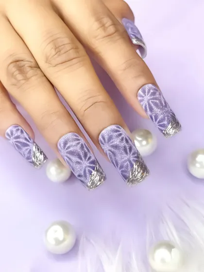 A beautiful lavender-colored nail set featuring a geometric pattern created with cat-eye polish and accented with silver foil on the tips.