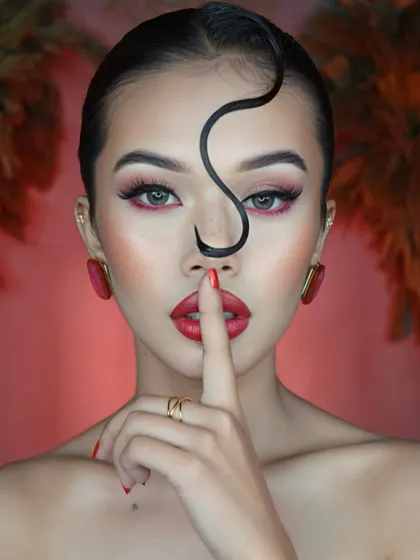 A playful and mysterious pose that draws attention to the bold red lips and the sharp, clean lines of the eye makeup.