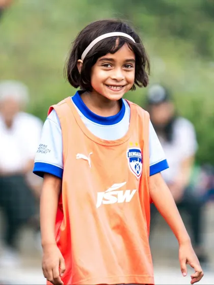 A young girl with a bright smile during the BFC AIFF Blue Cubs league. We are committed to growing the game for girls from the earliest ages.