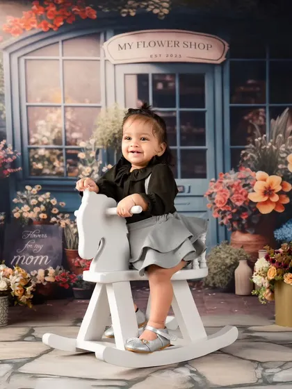 A first birthday shoot set against a charming flower shop backdrop. This little girl's smile is as bright as the flowers around her.