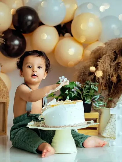 The aftermath of a successful cake smash. This little boy is enjoying his first taste of birthday cake in our popular bohemian-style studio set.