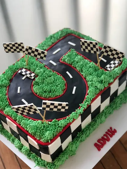 A racetrack cake in the shape of the number five, ready for the client to add their own toy cars at the party.