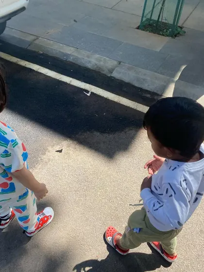 Two children walk side-by-side, exploring their neighborhood and observing the world around them.