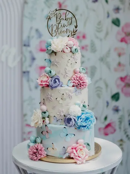 This three-tier "Baby in Bloom" cake was designed to match the floral backdrop of the event. It features multiple flavors like Vanilla Caramel and Dark Chocolate Nutella, all finished in beautiful buttercream.