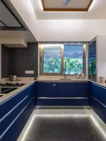 This U-shaped kitchen features bold blue cabinets and floor-level LED strip lighting, creating a unique and futuristic ambiance.
